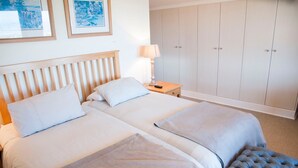 A double bed with two pillows, a bedside table with a lamp, and a wardrobe with two doors. - Villa 17 (Knysna)