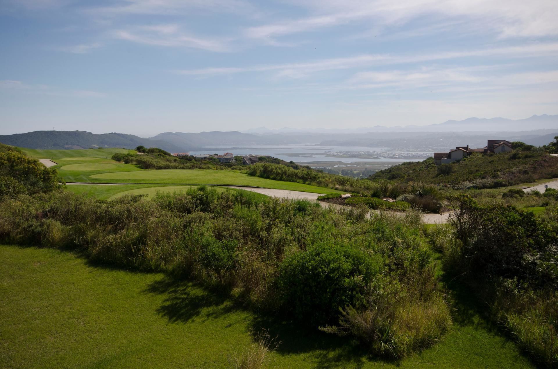 A golf course with a view of a body of water and distant mountains.