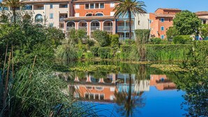 A hotel with multiple-story buildings, a reflective pond, and lush greenery.