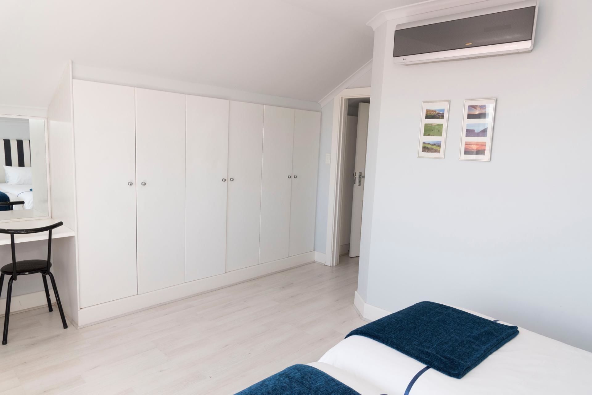 A bedroom with a bed, a desk, and a wardrobe.