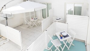 A patio area with a white umbrella, white folding chairs, and a small table with a flower vase. - Just 100 meters from one of the most beautiful and renowned beaches of the Ragusa’s coast (Marina di Ragusa)