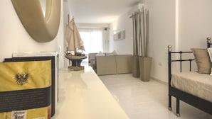 A modern hotel room with a bed, a sofa, a dining table, and a large mirror. - Just 100 meters from one of the most beautiful and renowned beaches of the Ragusa’s coast (Marina di Ragusa)