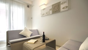 A cozy room with a sofa, a small table with a bottle and glasses, and a wall with a 'MER' sign. - Just 100 meters from one of the most beautiful and renowned beaches of the Ragusa’s coast (Marina di Ragusa)