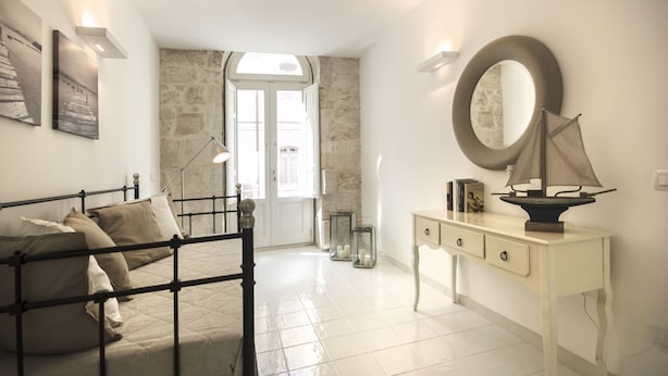 A bedroom with a bed, bedside table, mirror, and a view of the outside. - Just 100 meters from one of the most beautiful and renowned beaches of the Ragusa’s coast (Marina di Ragusa)