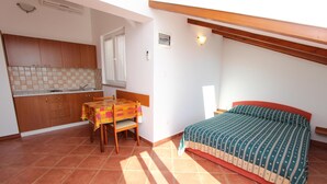 A compact room with a bed, a small table, and a kitchenette. - Apartments Elida (Rovinj)