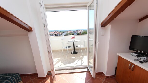 A balcony with a table and chairs, a television, and a sofa. - Apartments Elida (Rovinj)