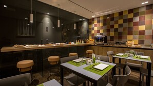 A modern restaurant with a central bar area, multiple dining tables, and a colorful tile backsplash. - Plebis - Camere & Suites in Sicilia nel centro storico di Catania (Catania)