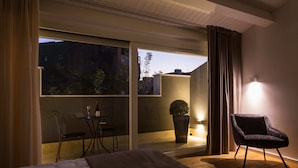 A hotel room with a bed, a chair, a small table with a glass, and a potted plant. - Plebis - Camere & Suites in Sicilia nel centro storico di Catania (Catania)