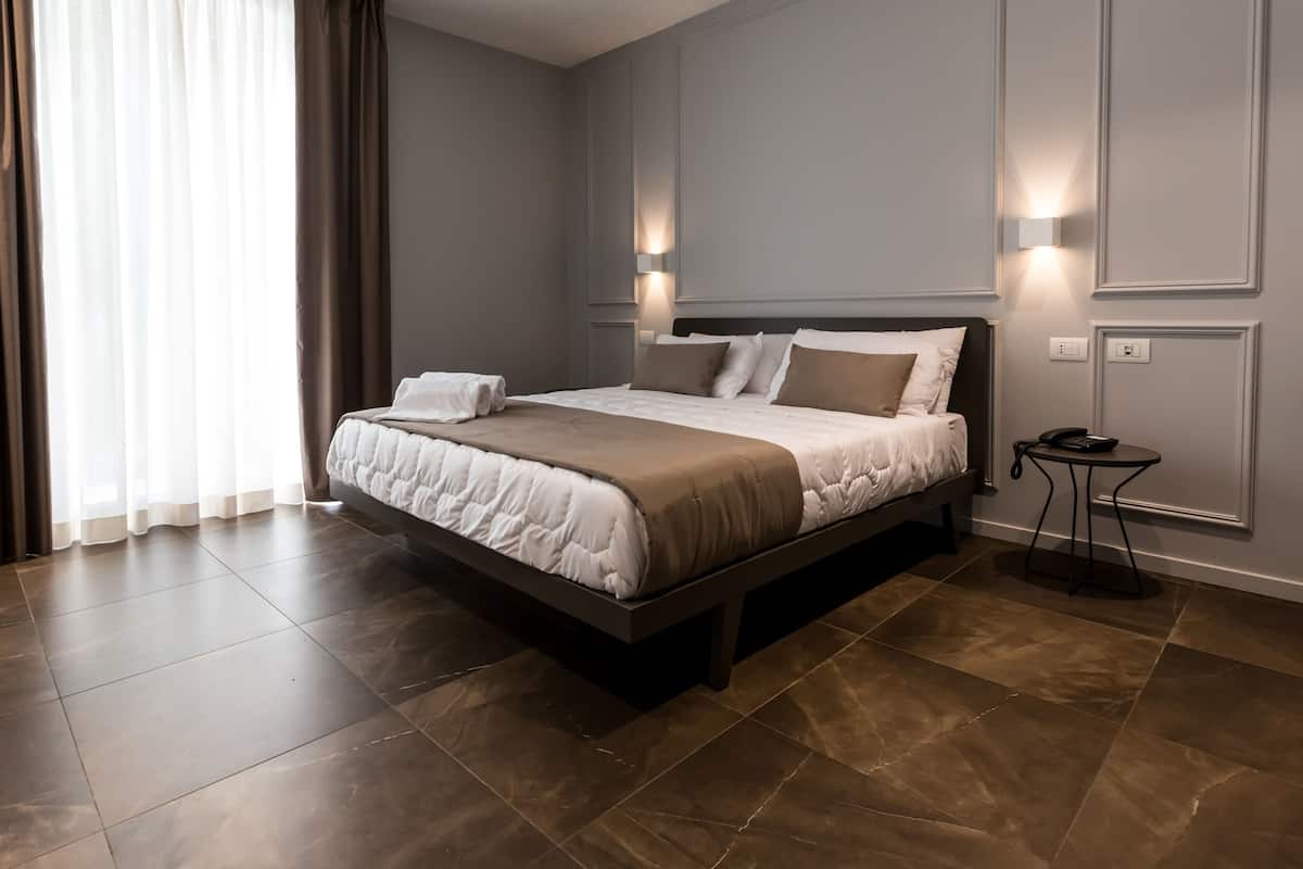 A modern hotel room with a large bed, two bedside tables, and a nightstand.