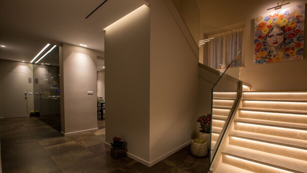 A modern interior with a staircase, recessed lighting, and a glass elevator. - Plebis - Camere & Suites in Sicilia nel centro storico di Catania (Catania)