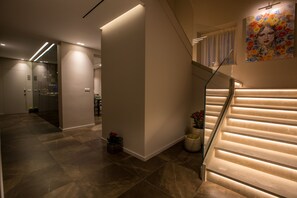 A modern interior with a staircase, recessed lighting, and a glass elevator. - Plebis - Camere & Suites in Sicilia nel centro storico di Catania (Catania)