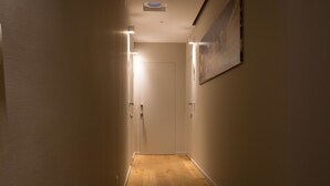 A narrow hallway with wooden flooring, white walls, and a door at the end. - Plebis - Camere & Suites in Sicilia nel centro storico di Catania (Catania)