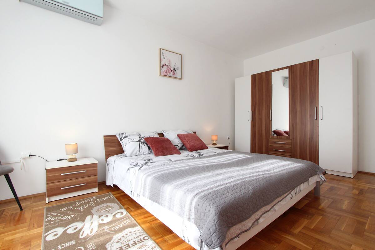 A bedroom with a bed, nightstands, a wardrobe, and a rug.