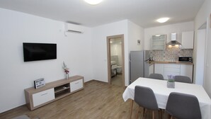 Ett modernt vardagsrum med en platt-TV, en möbel i trä för underhållningssystemet och en matplats med ett bord och stolar.
