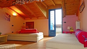 A cozy room with a bed, a sofa, and a door leading to a balcony. - Rustico Colonna (Tremosine)