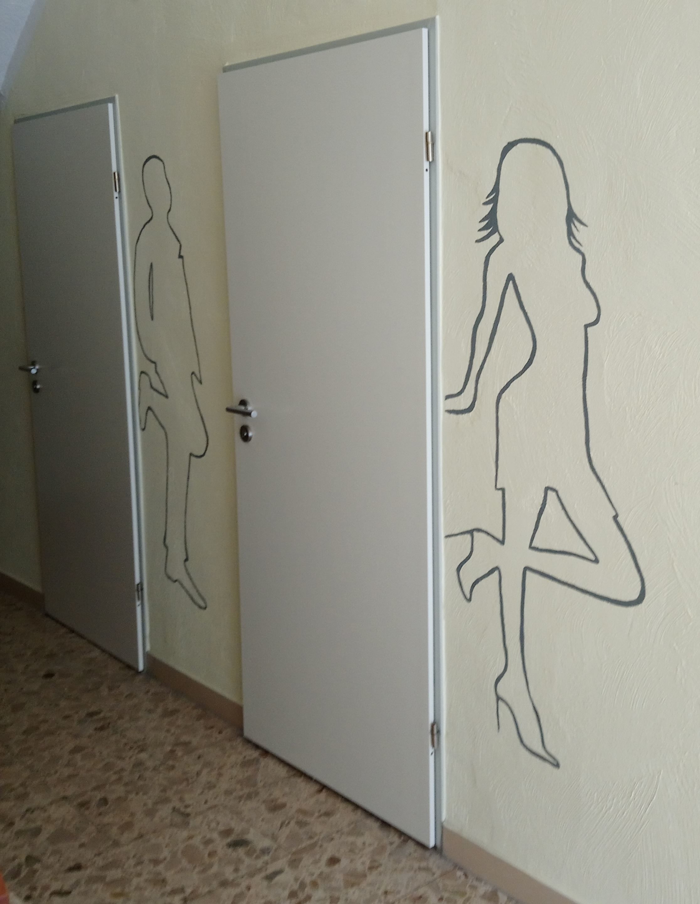 Um corredor com três portas, cada uma com um desenho simples de uma pessoa.