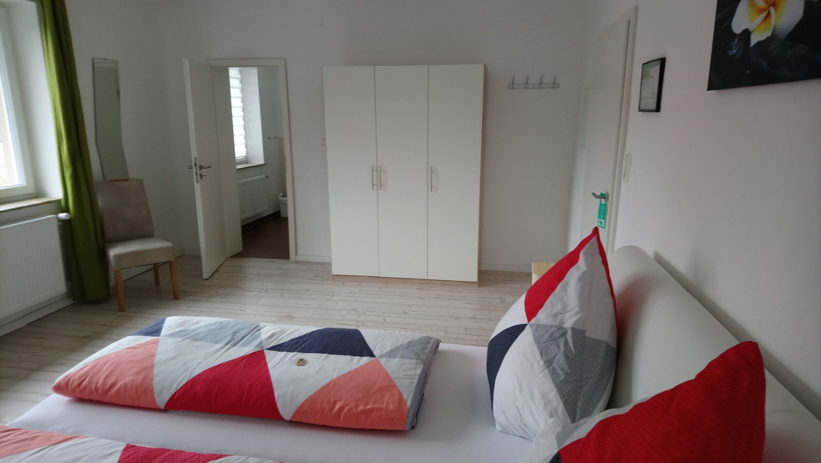 A bedroom with a bed, a wardrobe, a chair, and a window.