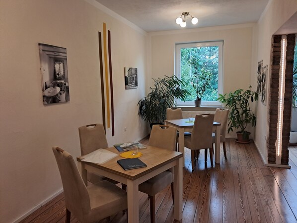 Un coin repas avec une table et des chaises en bois, une plante en pot et une fenêtre donnant sur un paysage verdoyant.