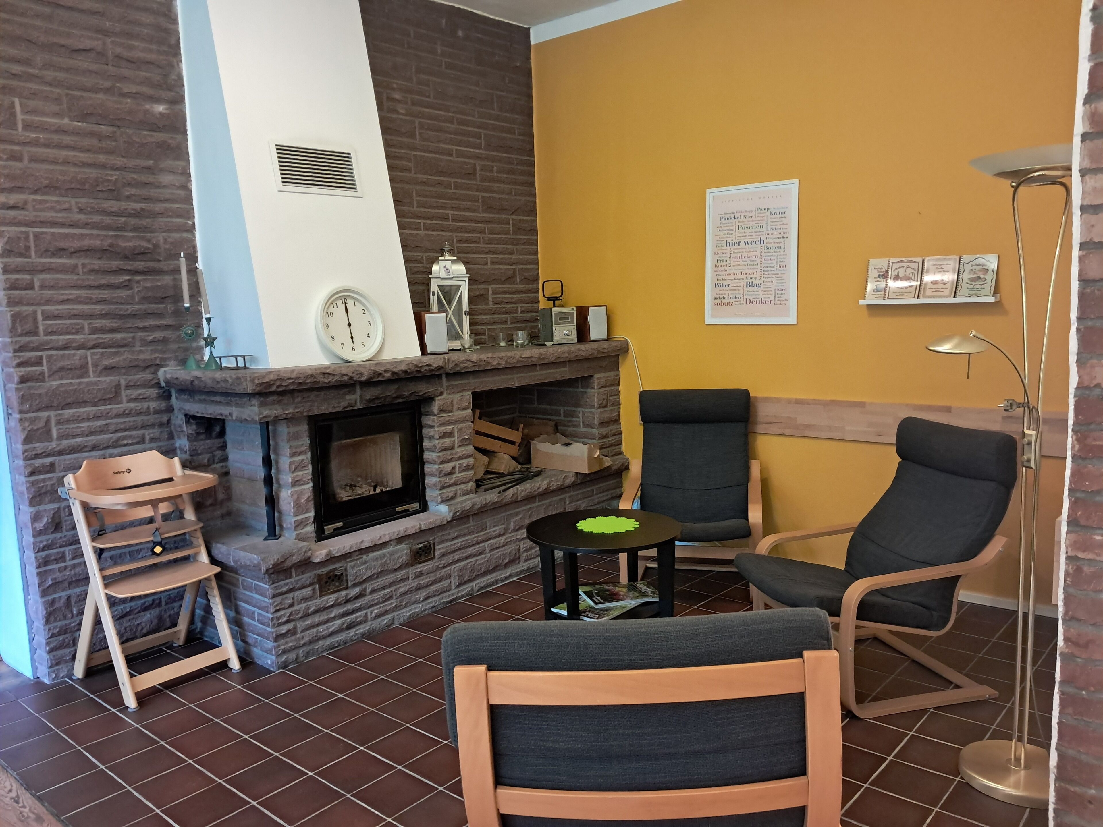 Una sala de estar acogedora con chimenea, dos sillones, una mesita y un reloj en la pared.