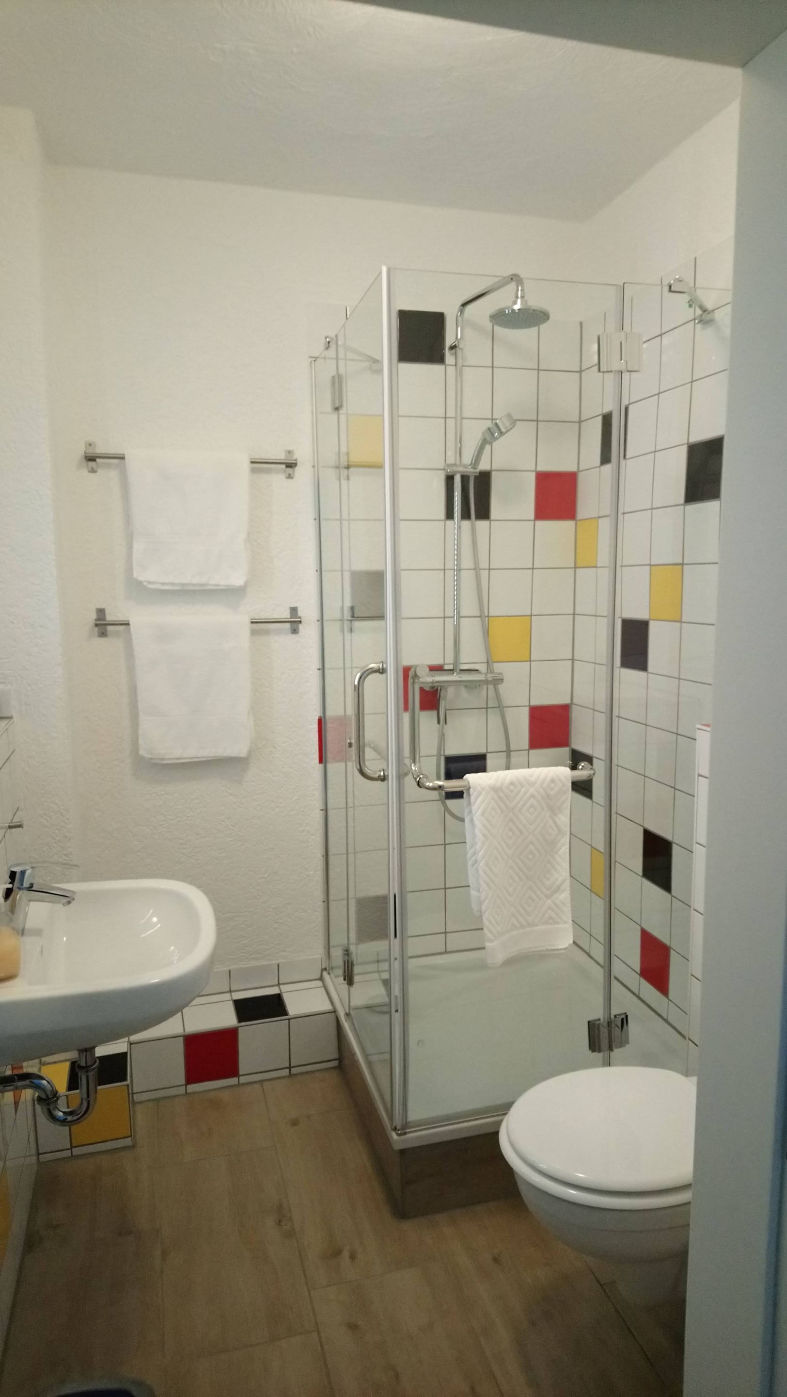 Ein Badezimmer mit einer Duschkabine, einem weißen Waschbecken und einer Toilette.