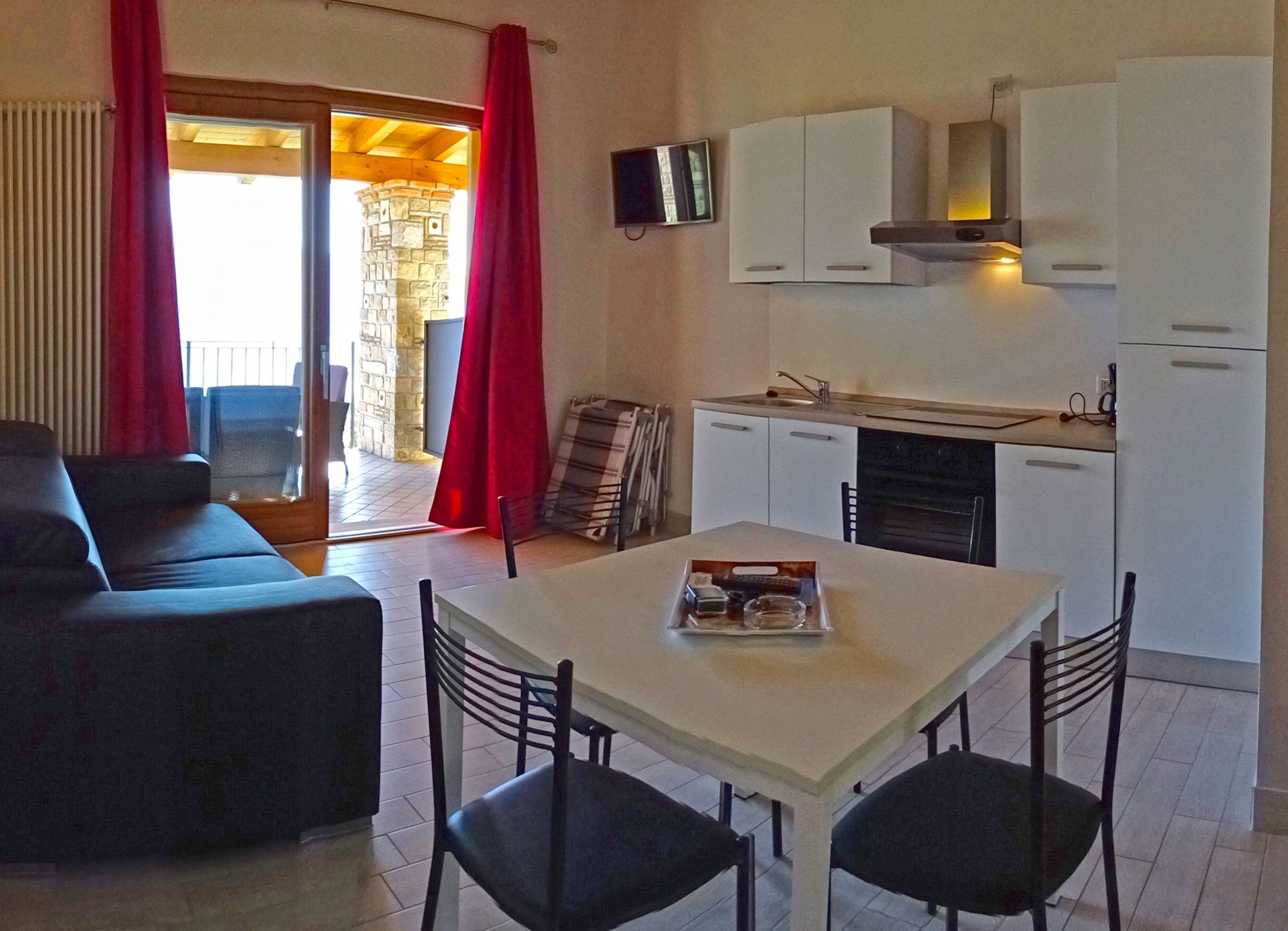 A compact living space with a dining area, kitchenette, and a view of the outside.
