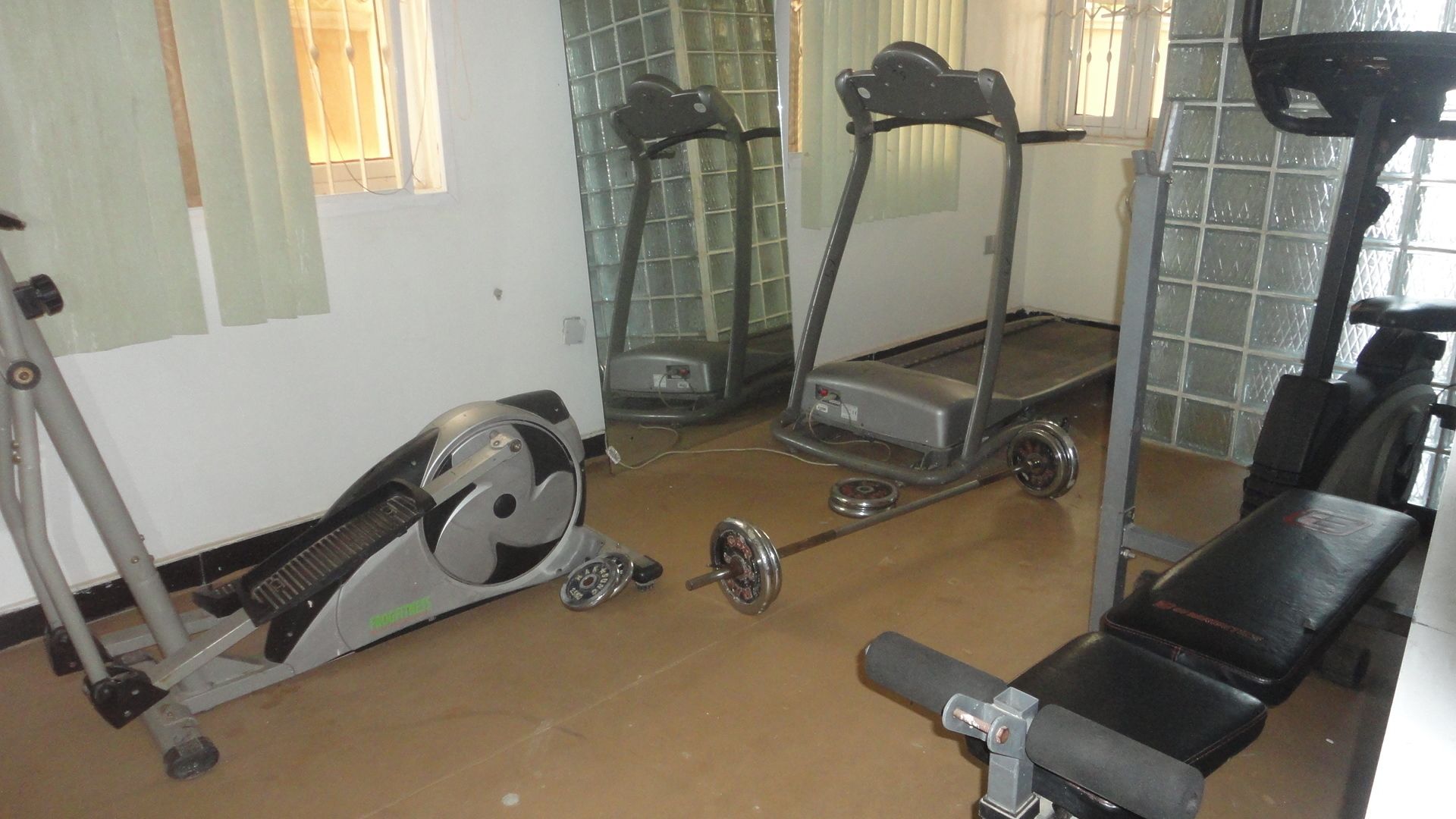 Ein Heimfitnessraum mit Ergometer, Crosstrainer, Laufband und Gewichten.