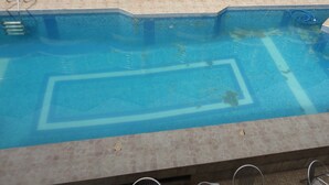 Une piscine avec un bord carrelé et une bordure en pierre.
