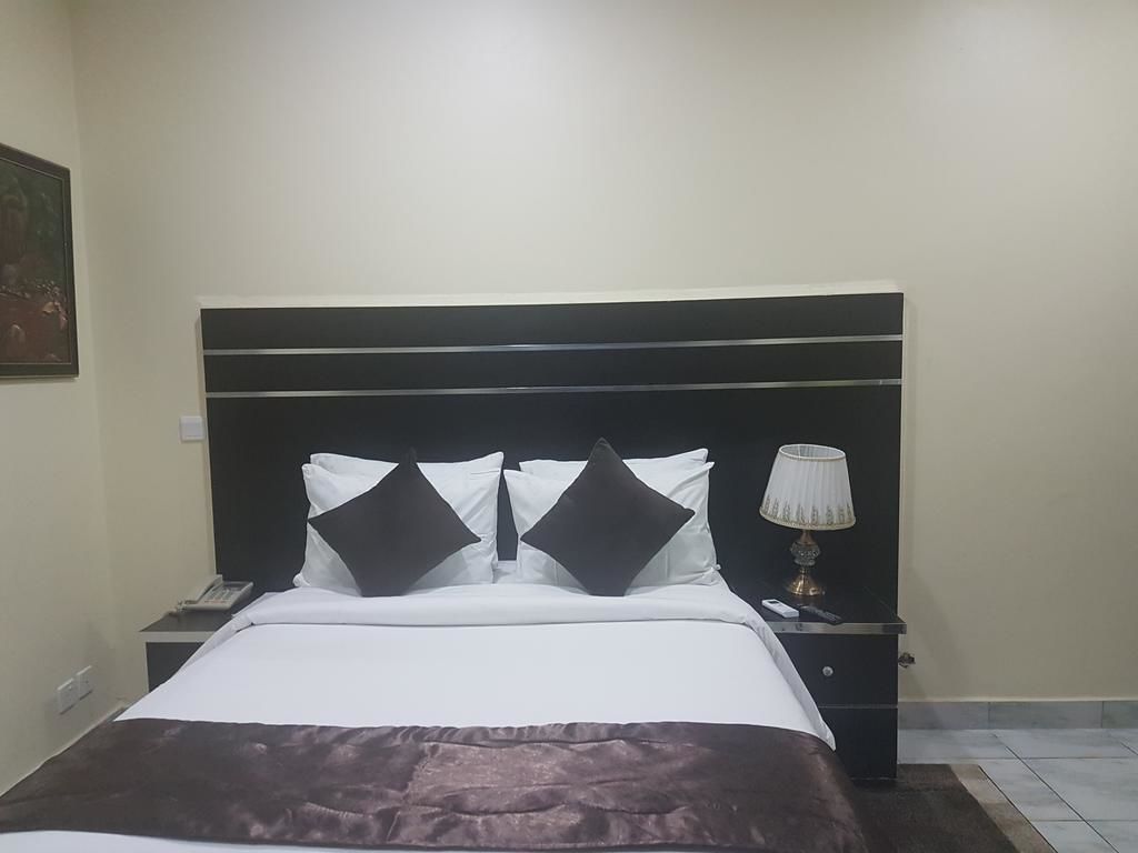 Habitació d'hotel amb un llit, una tauleta de nit, una làmpada i un quadre a la paret.