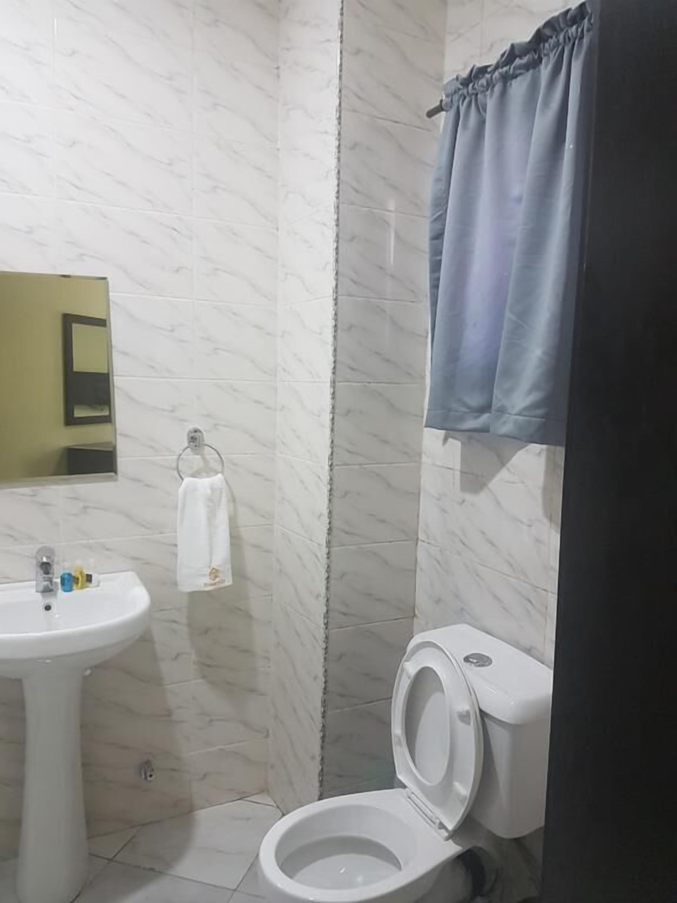 Uma casa de banho com uma pia branca, sanita e espelho.
