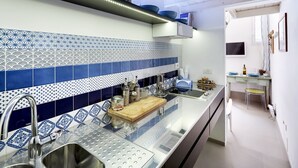 A modern kitchen with blue and white patterned tiles, stainless steel appliances, and a wooden cutting board. - Just 50 meters from one of the most beautiful and renowned beaches of the Ragusa’s coas (Marina di Ragusa)
