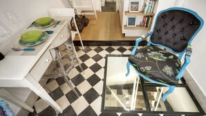 A dining area with a checkered floor, a dining table with green plates, and a blue upholstered chair. - Just 50 meters from one of the most beautiful and renowned beaches of the Ragusa’s coas (Marina di Ragusa)