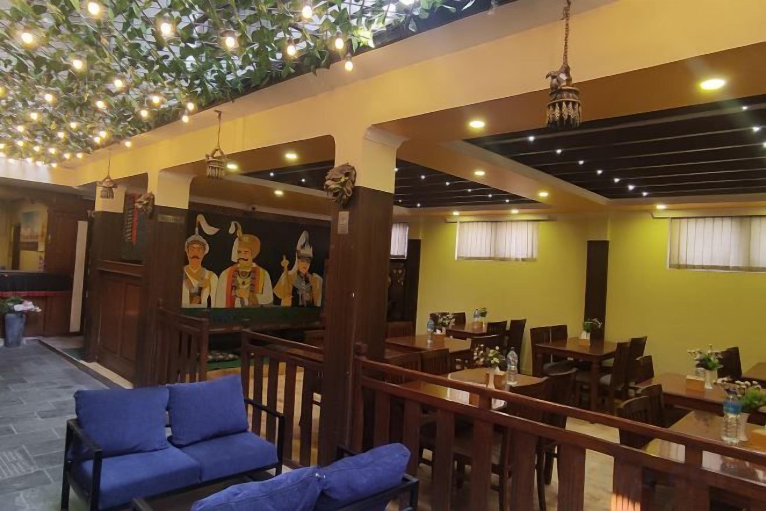 Restaurante com móveis de madeira, luminárias pendentes e um mural.