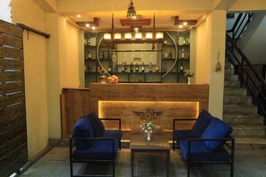 A lobby with a reception desk, a bar area with shelves of bottles, and a staircase. - Royal Kings Hotel (Kathmandu)