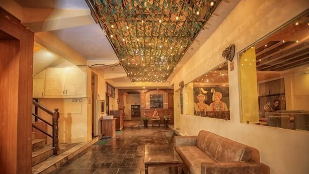 Eine Lobby mit Treppe, einer Couch, einem Chandelier und einer Wand mit einer Statue.