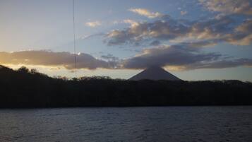 Silueta de montaña contra un cielo al atardecer, con una masa de agua en primer plano.