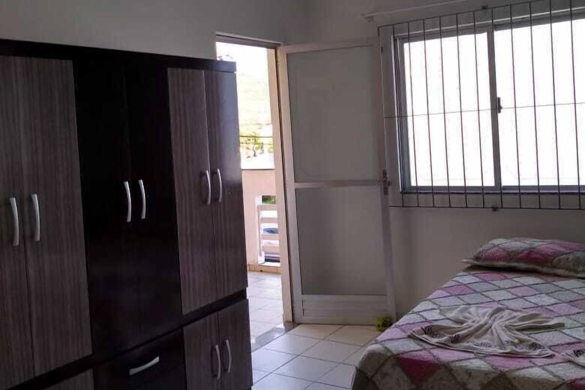 A bedroom with a bed, wardrobe, and a window with bars.