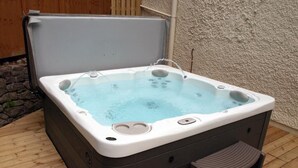 A hot tub with a wooden deck and a step for entry. - The Coachhouse (Colwyn Bay)