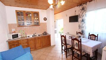 Una cocina con armarios de madera, microondas y comedor con mesa y sillas.