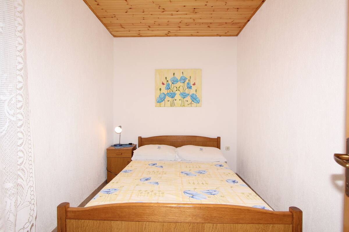 Ein Schlafzimmer mit einem hölzernen Bett, einem Nachttisch, einer Lampe und einem Bild an der Wand.