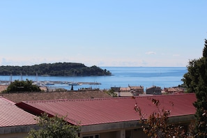 A coastal town with red-roofed buildings, a marina, and a small island in the distance. - Apartments Giorgia (Rovinj)