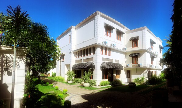 A multi-story hotel with a symmetrical facade, large windows, and a well-maintained garden.