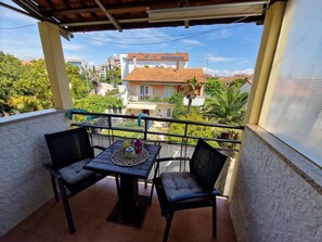 Un balcón con una mesa y dos sillas, con vistas a una zona residencial con casas y vegetación.