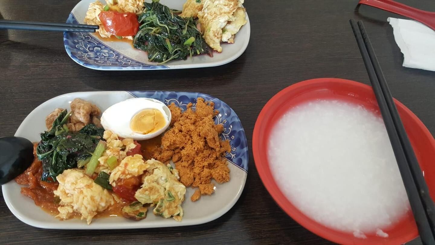 Two plates of food with chopsticks and a bowl of white substance, likely rice, on a table.