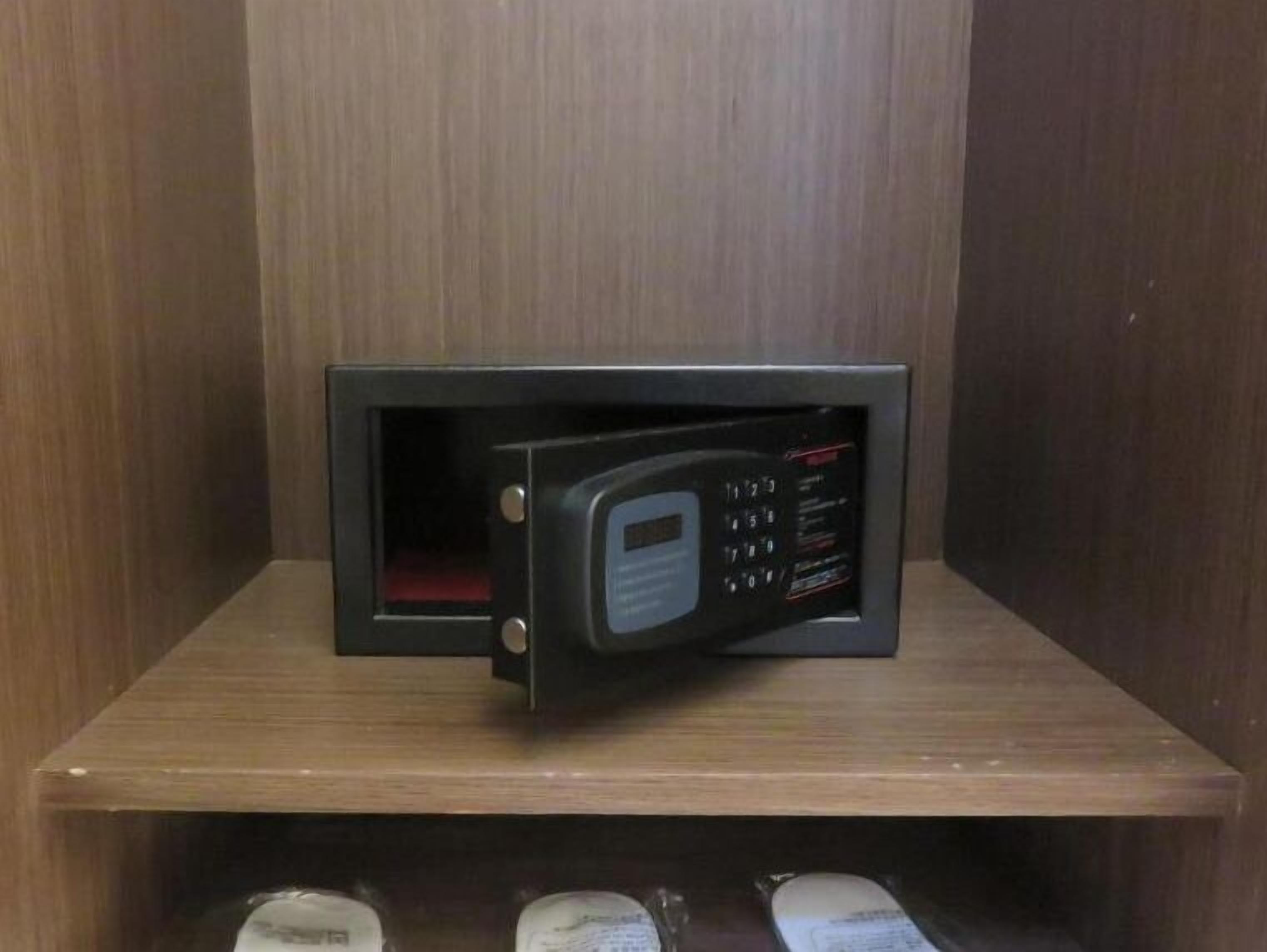 A microwave on a wooden shelf in a kitchen.