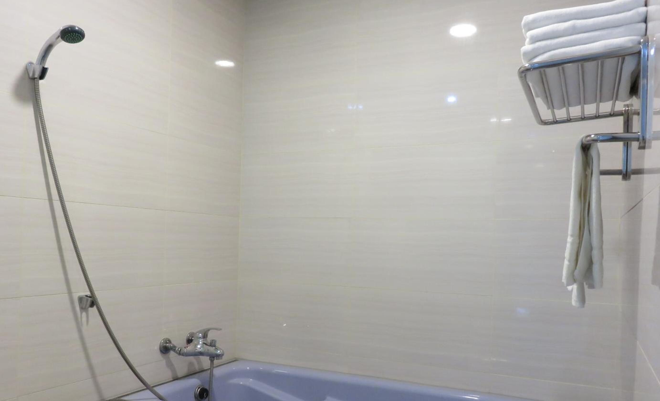 Un baño con bañera, cabezal de ducha y toallero con toallas.