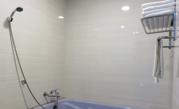 A bathroom with a bathtub, a showerhead, and a towel rack with towels. - Maohua Motel (Taichung)
