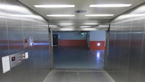 L’intérieur d’un ascenseur, avec des parois métalliques, un panneau de commande et un indicateur de niveau.