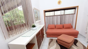 Ein modernes Wohnzimmer mit weißem Schreibtisch, einer Couch und einem Fenster mit Vorhängen.