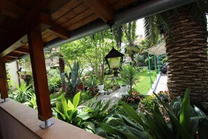 A covered outdoor area with a wooden ceiling, potted plants, and a pathway leading to a garden. - Apartments Goga (Rovinj)