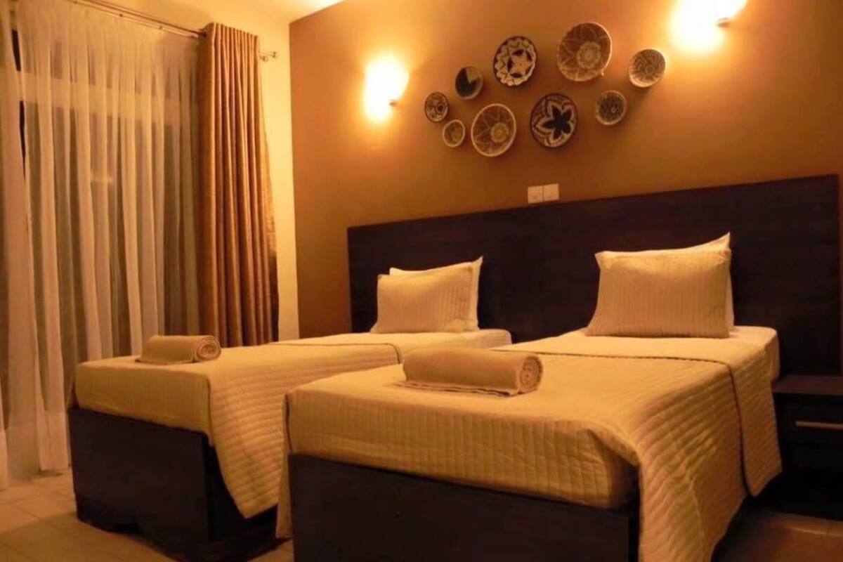 Habitación de hotel con dos camas, cabecero y pared decorada con platos.